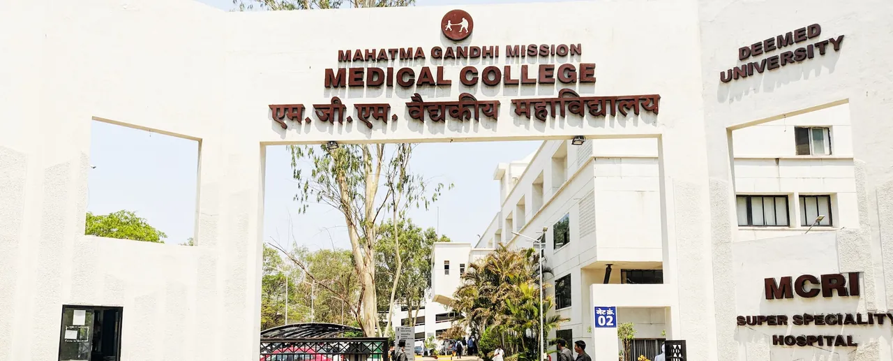 The entrance gate of Mahatma Gandhi Mission Medical College with its name in English and Marathi, the college building visible through the arch.