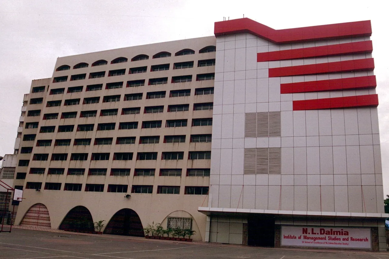 The N. L. Dalmia Institute building from the forecourt, beige with red bands, the institute's name board over the entrance.