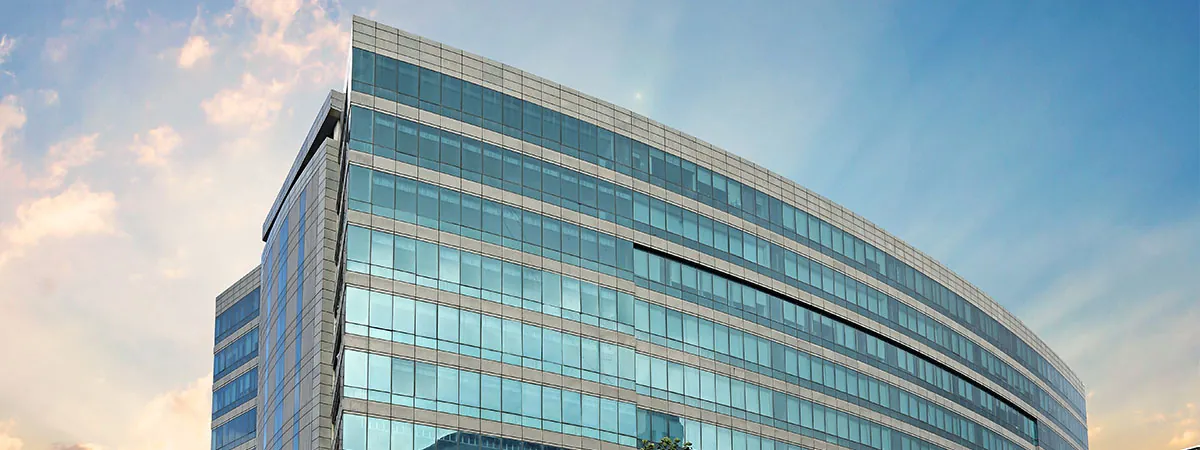 The curved blue-glass NMIMS Mumbai campus building against the sky. Wide banner crop (1200 x 450); a different file from the one recorded for the School of Business Management but the same building.