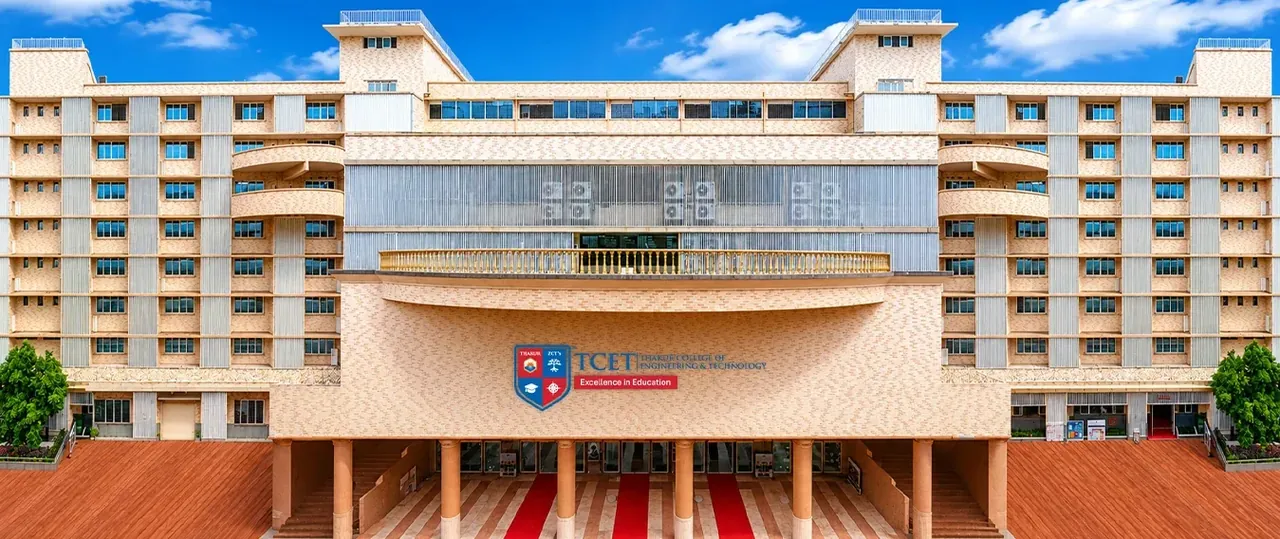 The front of the TCET building, symmetrical, with the TCET crest over the entrance canopy and red carpets on the steps, blue sky.