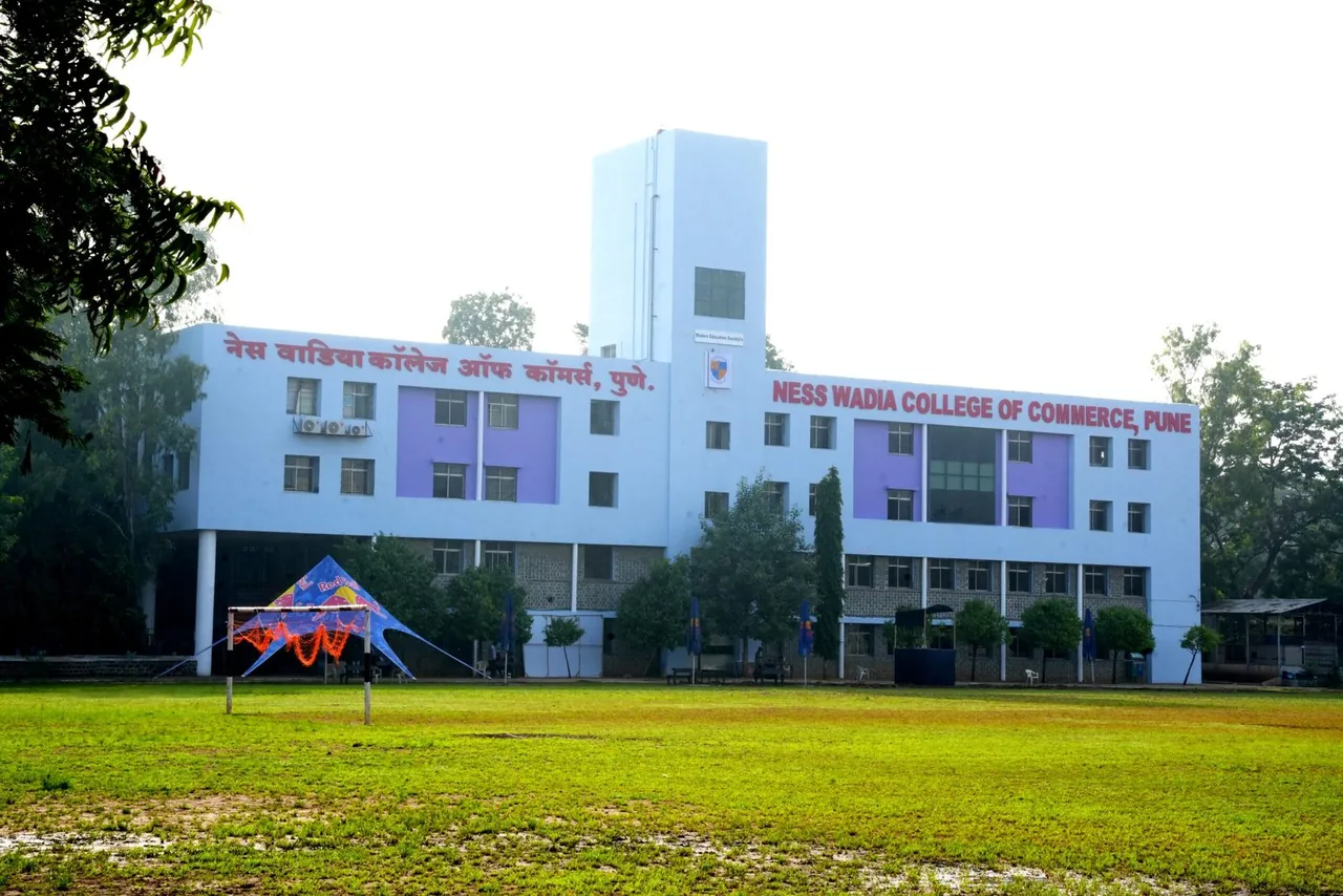 The Ness Wadia College of Commerce building with its name across the front, seen over the playing field